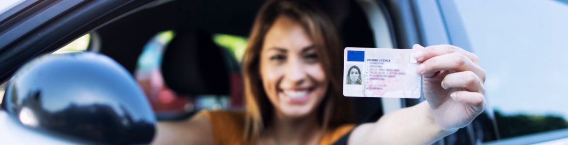 Mujer en coche enseñando carnet de conducir